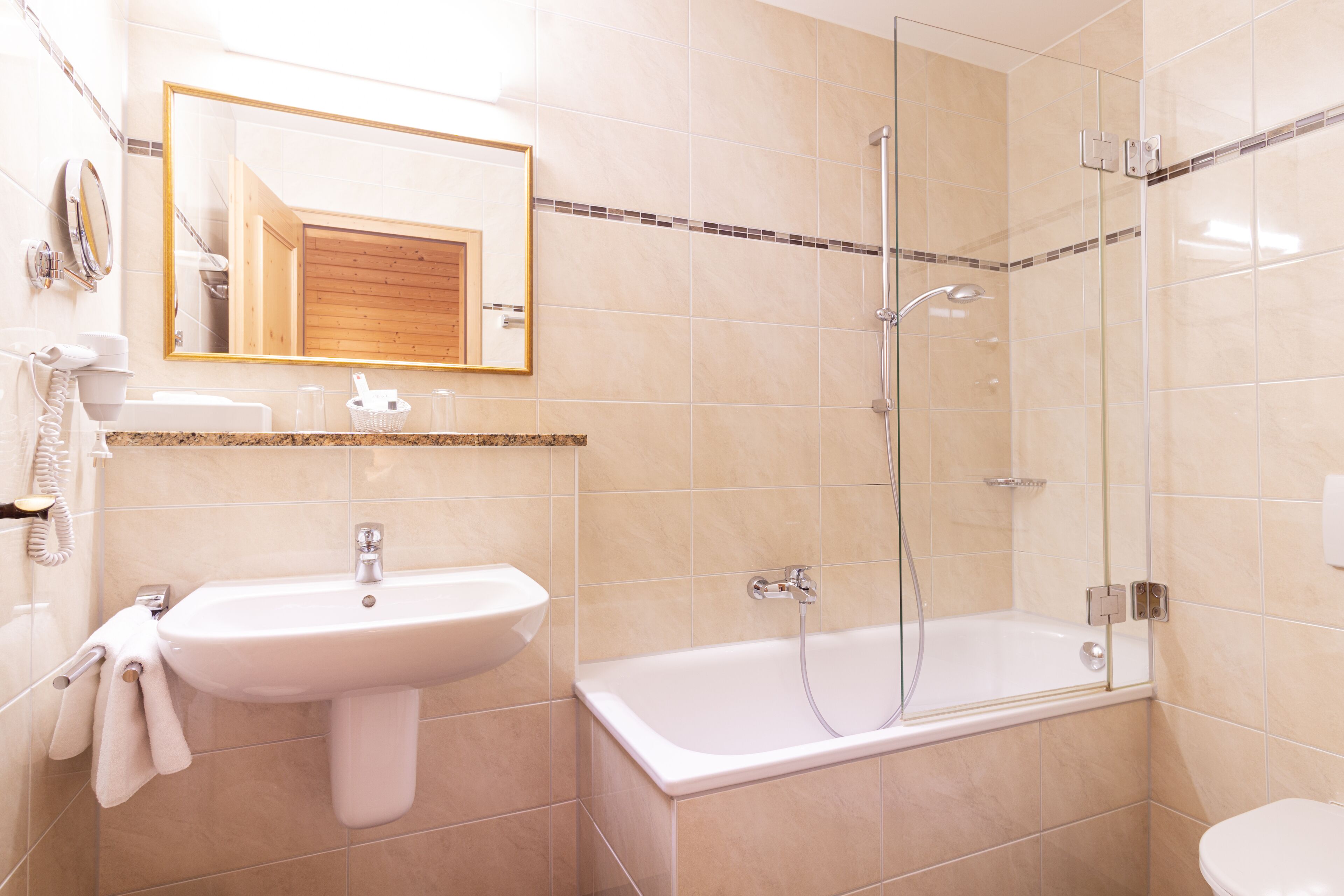 A modern bathroom with a sink, mirror, and glass-enclosed shower.