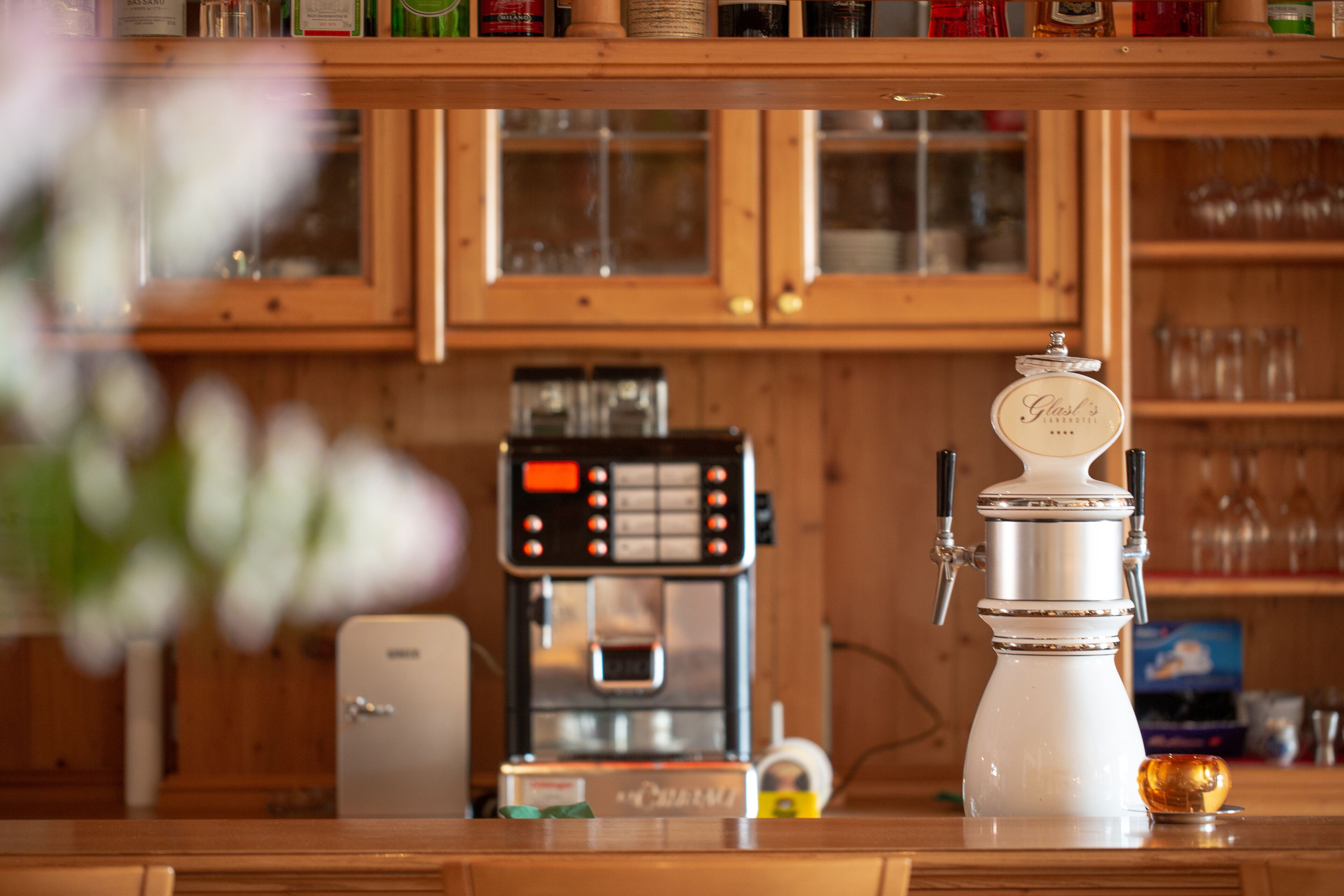 A kitchen with wooden cabinets, a coffee machine, and a glass carafe on the counter.