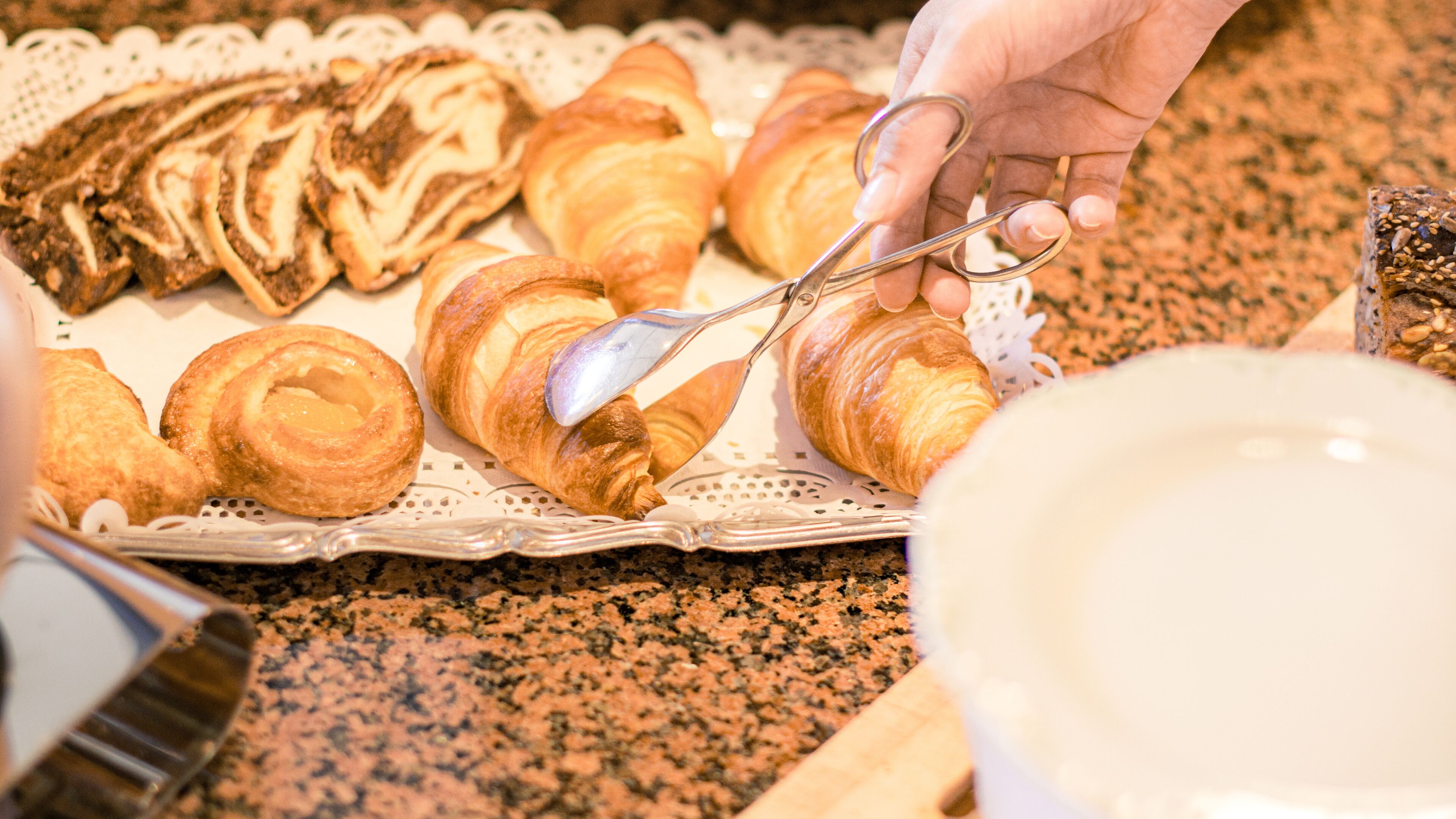 A tray of assorted pastries, including croissants and a marble roll, on a table.