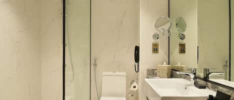 Ein modernes Badezimmer mit einer Glasduschkabine, Toilette, Waschbecken und einem großen Spiegel.