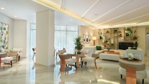 A spacious living room with a modern design, featuring a sofa set, a coffee table, and a dining area with chairs.