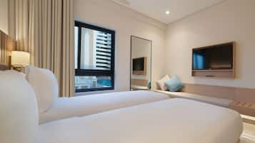 Une chambre d’hôtel moderne dotée d’un grand lit, d’un téléviseur fixé au mur et d’une fenêtre donnant sur un immeuble et une piscine.