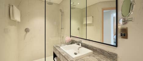 A modern bathroom with a marble sink, a glass shower enclosure, and a large mirror.