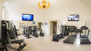 A gym with various exercise equipment, including treadmills, stationary bikes, and weight machines. - Villa Fenaroli Palace Hotel (Rezzato)