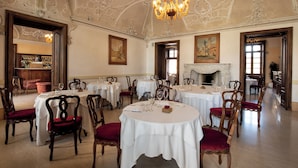 A dining room with round tables, wooden chairs, and a chandelier. - Villa Fenaroli Palace Hotel (Rezzato)