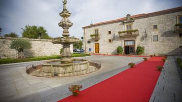 Un patio con una fuente, una alfombra roja y un edificio de piedra con balcones.