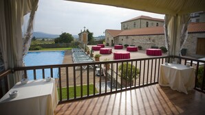 Una terraza con mesas y sillas, una piscina y vistas a un edificio con una cruz en la parte superior.