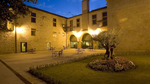 Un patio con edificios de piedra, mobiliario exterior y un jardín bien cuidado.