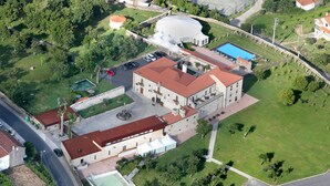 Vista aérea de un edificio histórico con un patio, piscina y cancha de tenis.