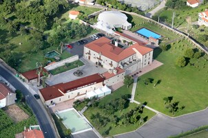 Vista aérea de un edificio histórico con un patio, piscina y cancha de tenis.
