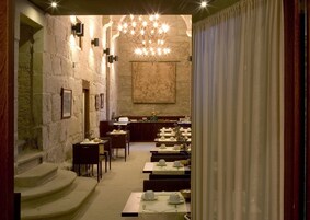 Un restaurante con paredes de piedra, un candelabro y mesas dispuestas para comer.