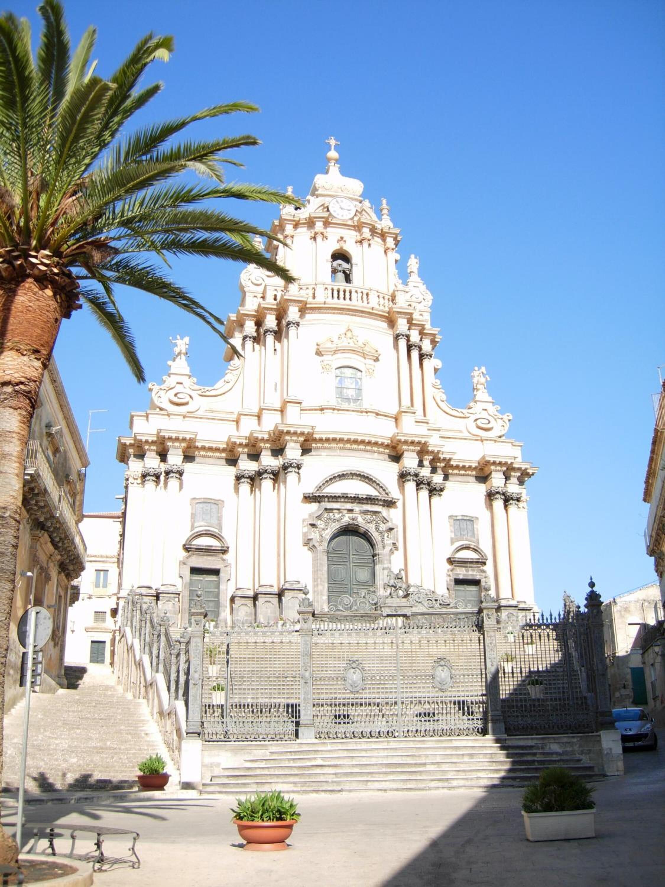 A historic church with ornate architecture, a bell tower, and a gated entrance.