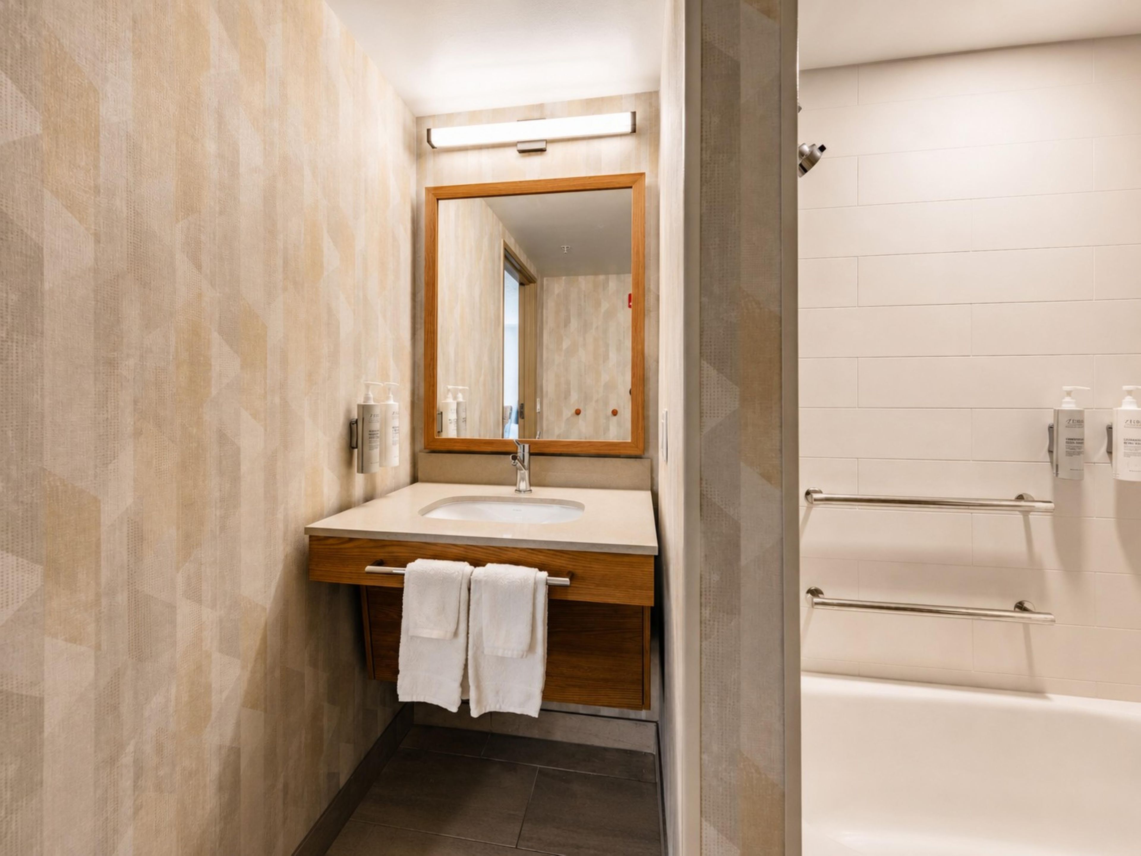 Un baño con tocador de madera, un espejo, un lavamanos y una bañera.