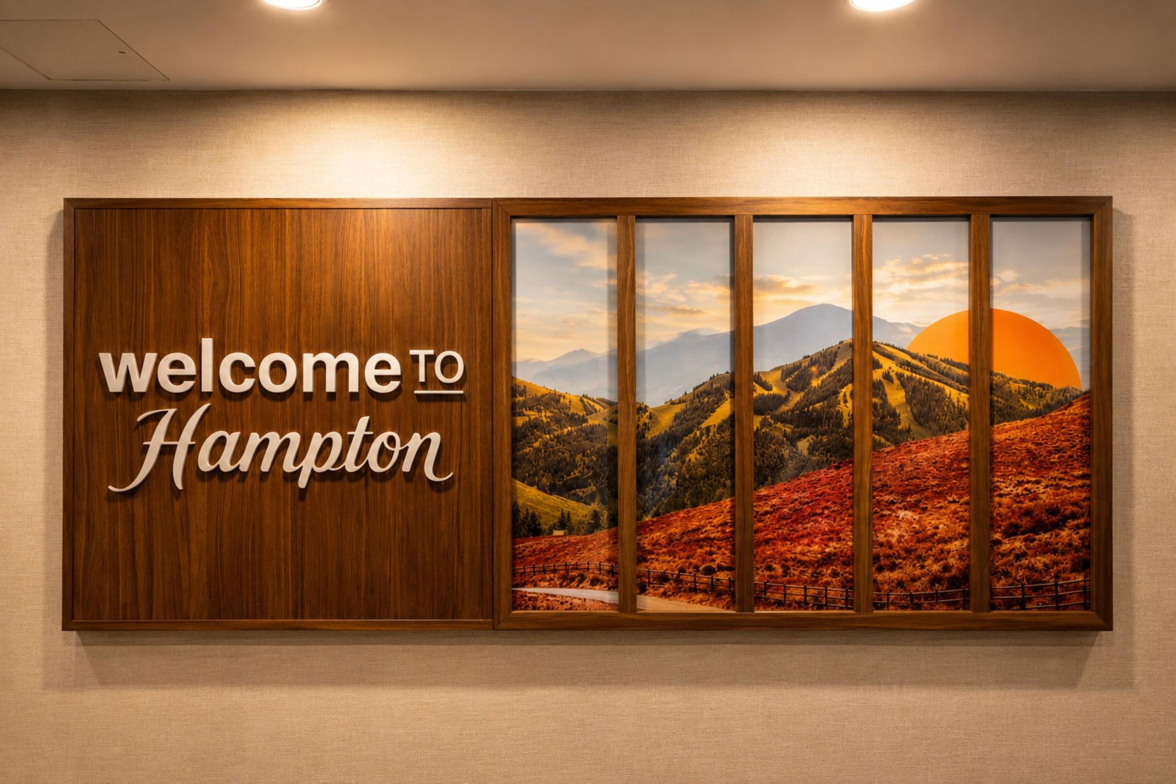 A welcome sign with 'welcome to Hampton' and a scenic landscape with mountains and a sunset.