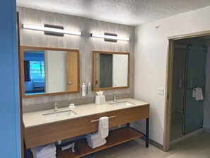 A modern bathroom with two mirrors, a sink, a vanity, and a glass shower enclosure. - Hampton Inn by Hilton Hailey Sun Valley (Hailey)