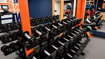 Et fitnessrum med rækker af håndvægte, løbebånd og træningsbolde.