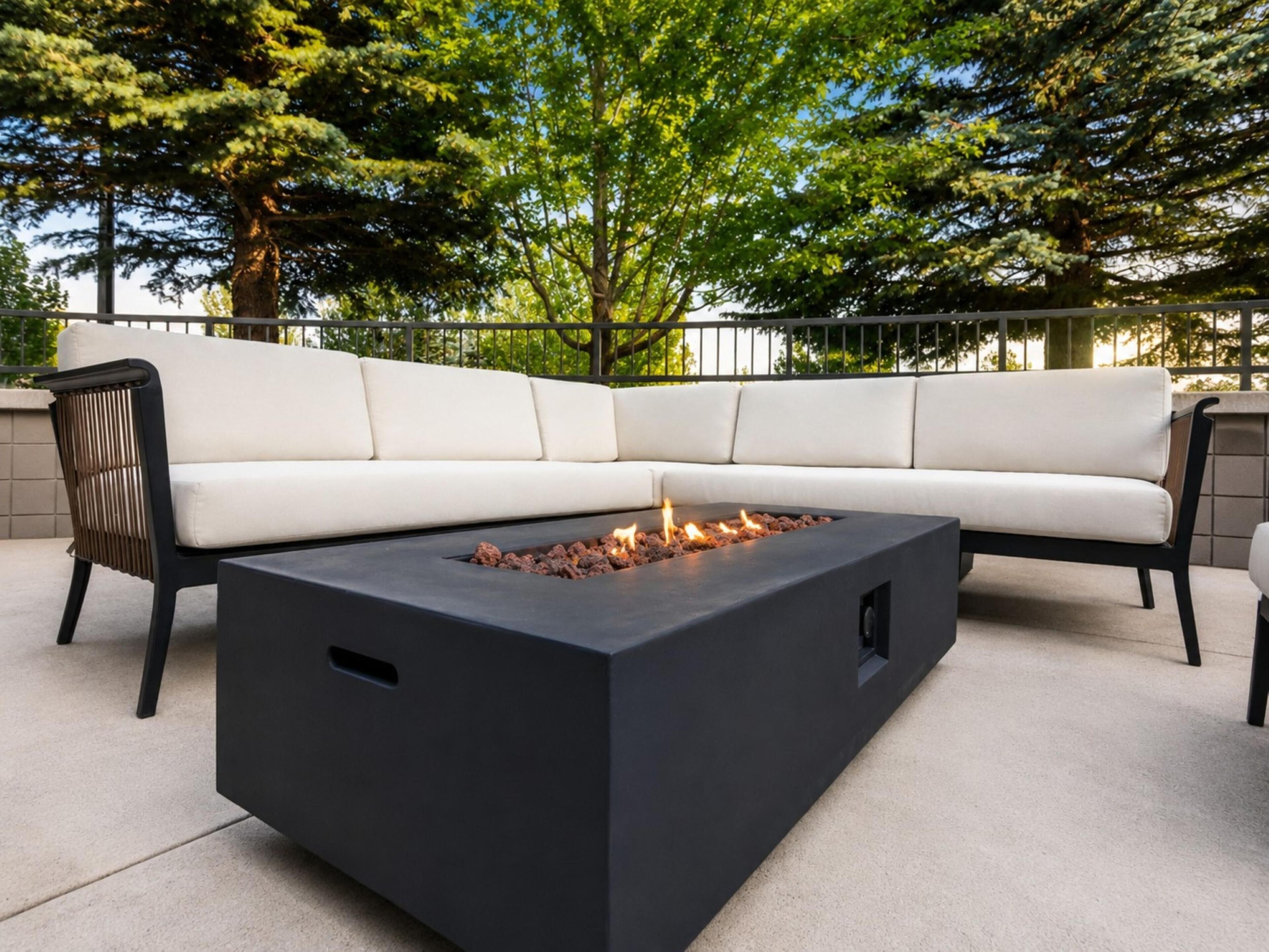 A modern outdoor seating area with a black fire feature and a white sofa.