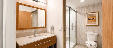 A bathroom with a wooden vanity, a glass shower enclosure, and a toilet.
