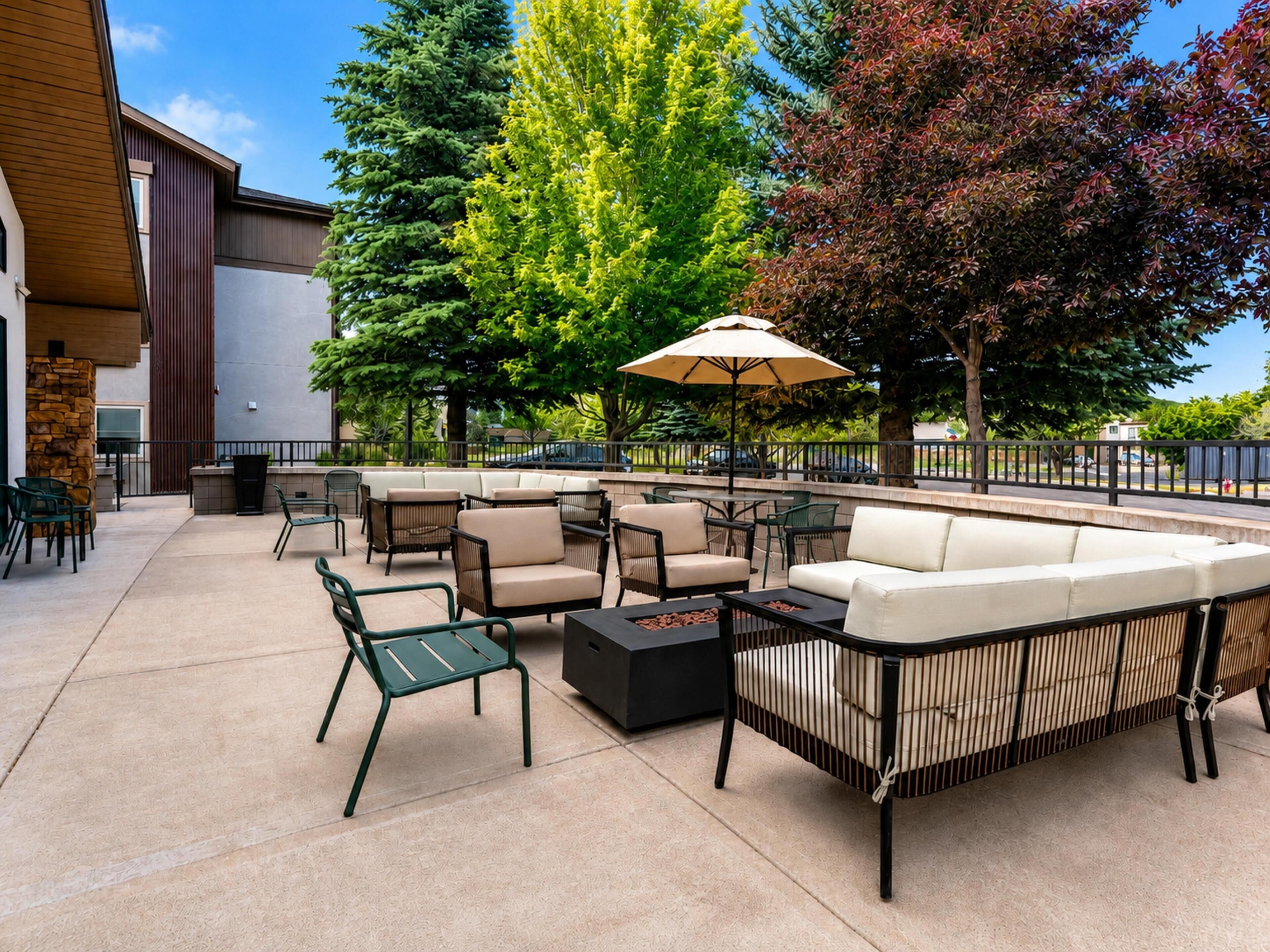 An outdoor patio area with seating arrangements, a table, and a large umbrella.