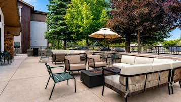 An outdoor patio area with seating arrangements, a table, and a large umbrella.