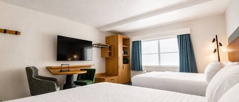 A hotel room with two beds, a desk, a TV, and a wardrobe.