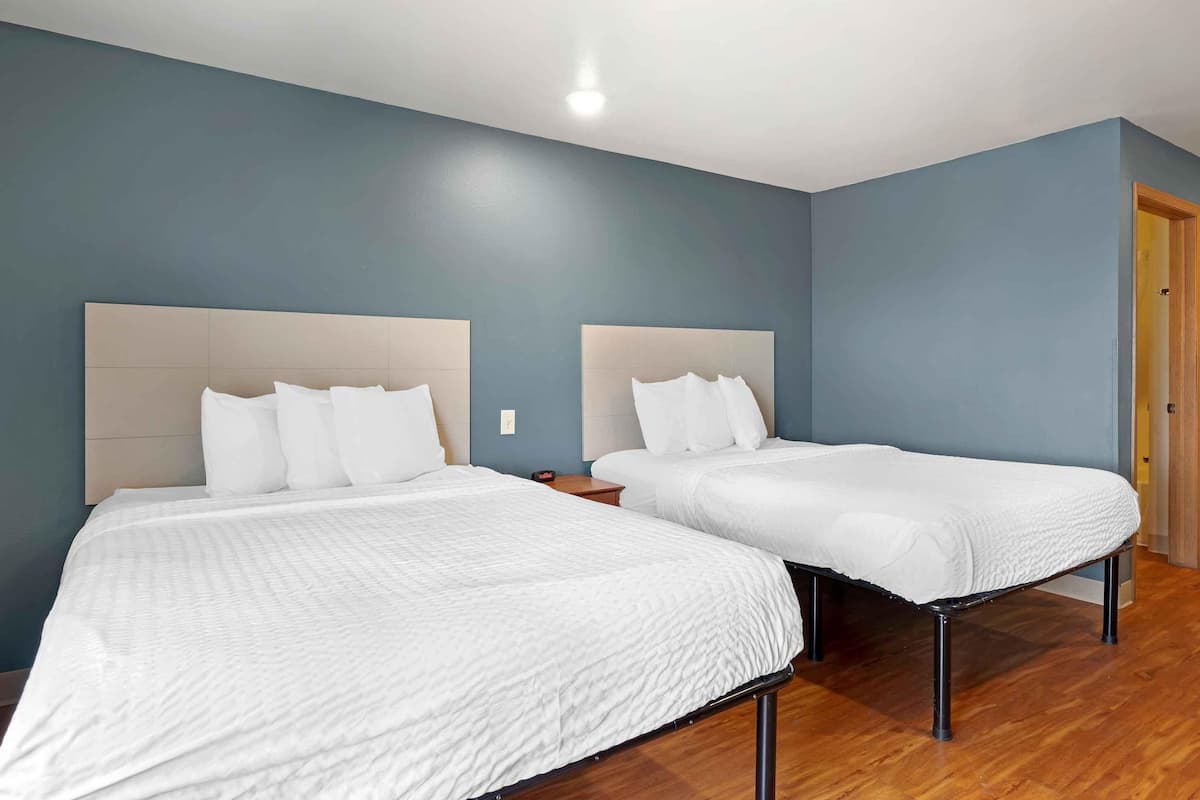 Una habitación con dos camas, suelo de madera y una puerta.