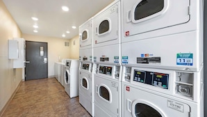 A laundry facility with multiple washing machines, a door, and a wall-mounted control panel. - Extended Stay America Select Suites - Wichita - Airport (Wichita)