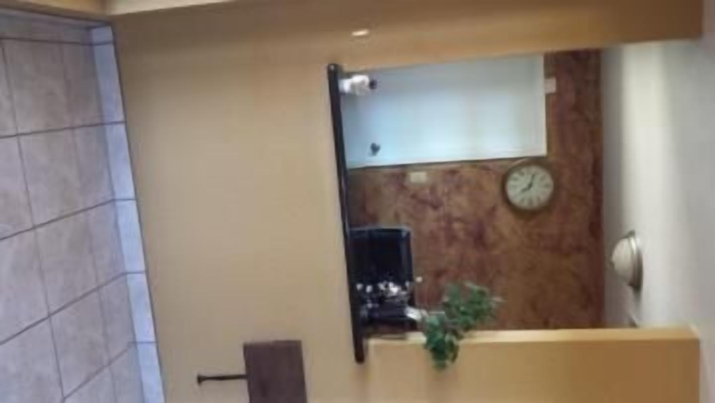 A reception area with a wooden reception desk, a clock on the wall, and a plant.