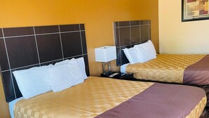 Ein Hotelzimmer mit zwei Betten, jeweils mit Kopfteil, Nachttisch und Lampe.