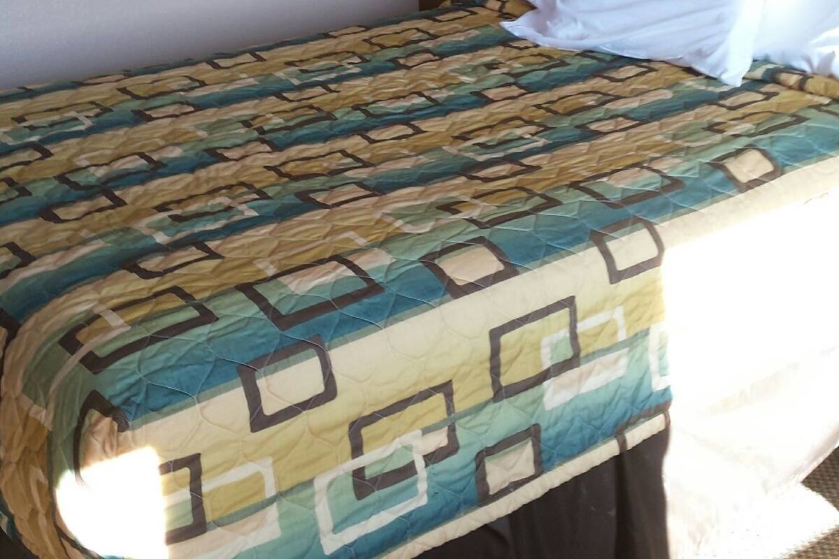 A hotel room with a bed, a headboard, a framed picture on the wall, and a carpeted floor.