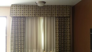 Ein Zimmer mit einem gemusterten Vorhang, einer Deckenleuchte und einer Tür.
