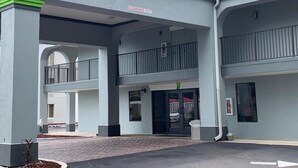 Un bâtiment avec une pancarte indiquant une « hauteur libre de 3,6 mètres », une entrée abritée et un balcon au deuxième étage doté d’une balustrade.