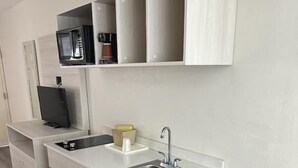 Une cuisine moderne avec des meubles blancs, un réfrigérateur noir, un four à micro-ondes encastré et un évier.