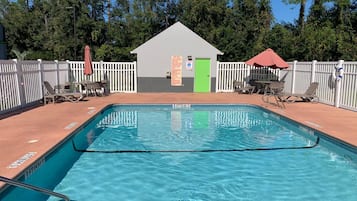 Relax by the pool surrounded by lounge chairs and umbrellas, with a changing room nearby.
