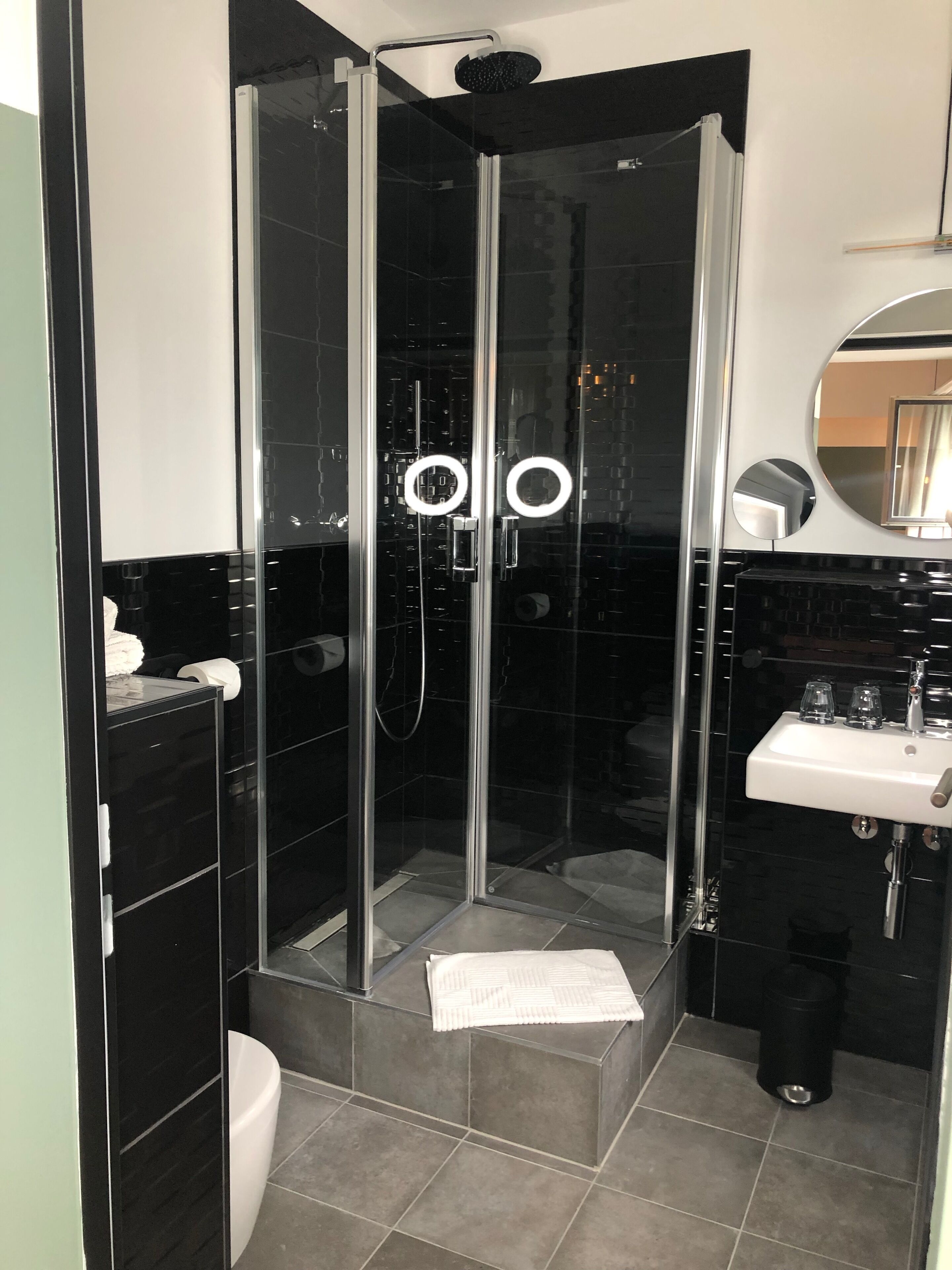 A modern bathroom with a glass-enclosed shower, a white sink, and a mirror.