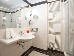 Un baño moderno con lavamanos, espejo y barra para toallas blancos.
