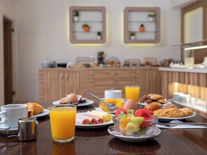 A breakfast buffet with various food items and drinks on a wooden table. - Athinaikon (Heraklion)