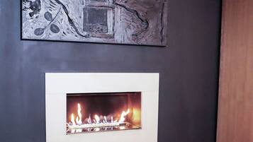 A modern living room with a fireplace, a black furry rug, and a piece of abstract art on the wall.