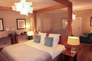 Habitación de hotel con una cama grande, dos lámparas de noche, una mesita de noche, una ventana con vistas y una silla en la esquina.