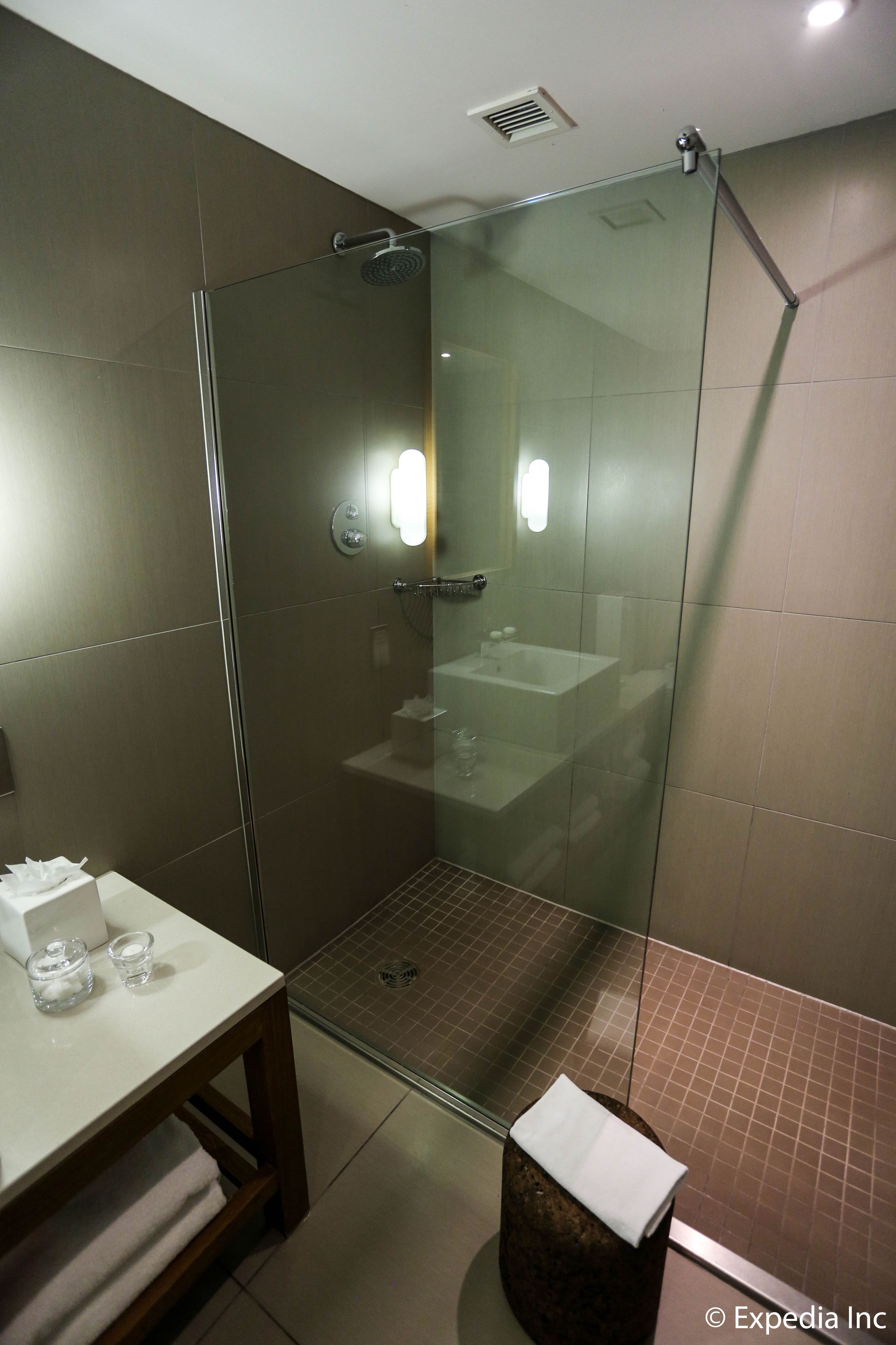 Un baño moderno con ducha de vidrio, un lavabo blanco y una pequeña mesa con una toalla.
