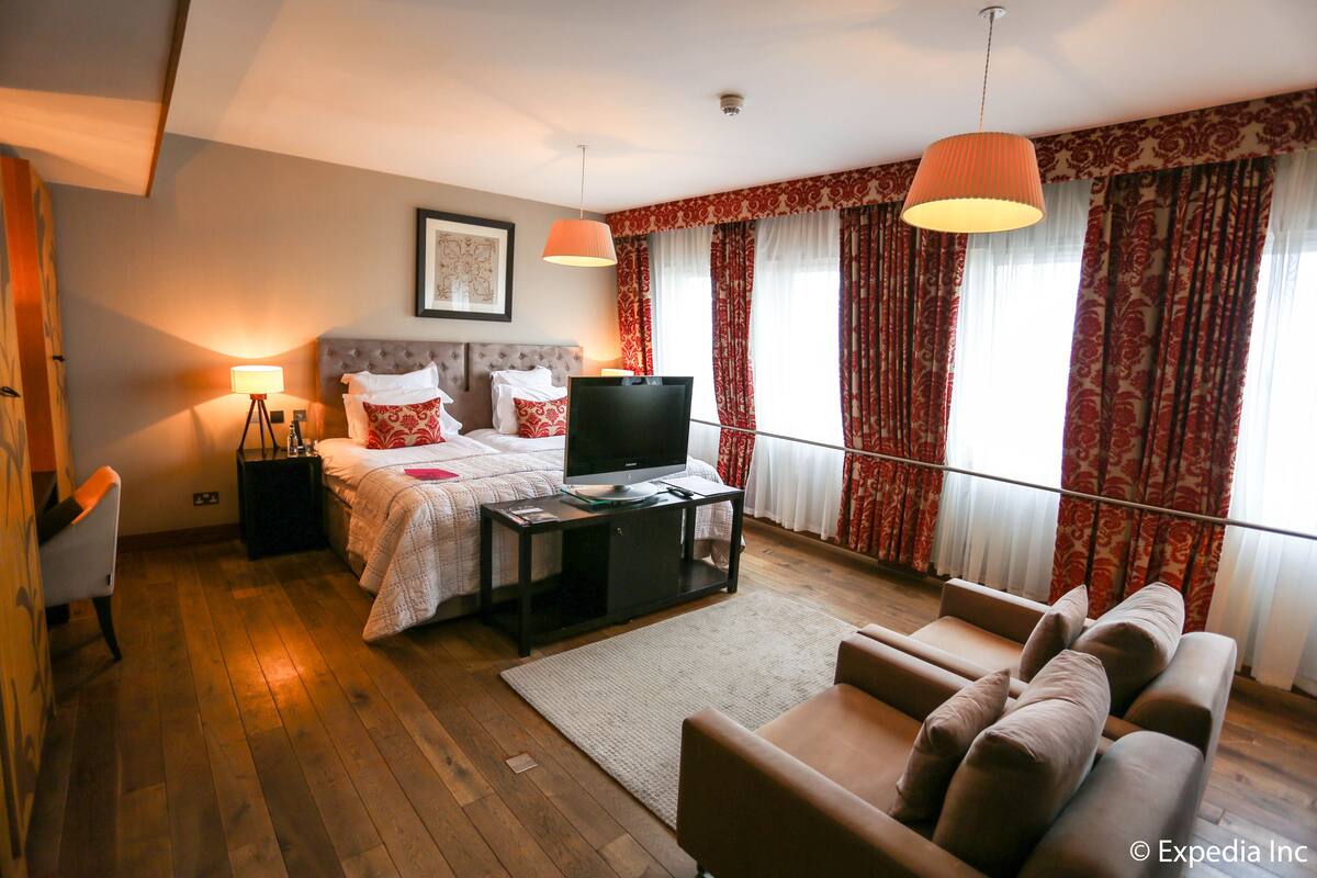 Una habitación de hotel con una cama, televisión, sofá y escritorio.