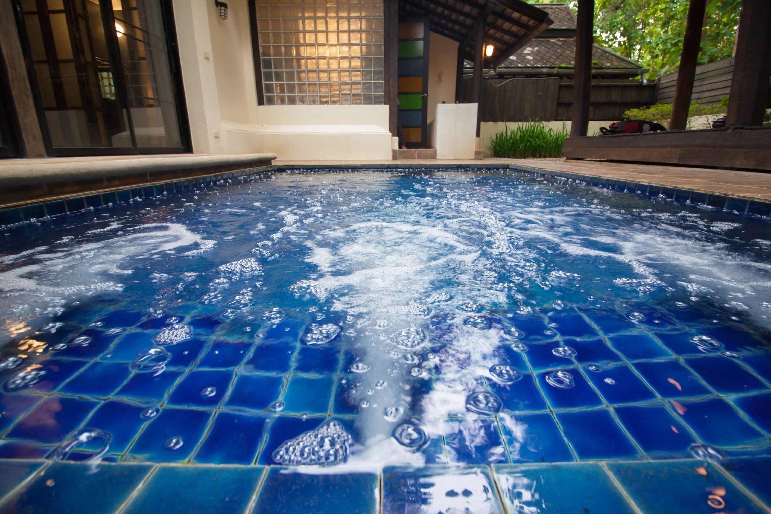 Un jacuzzi con piso de baldosas y muelle de madera alrededor.