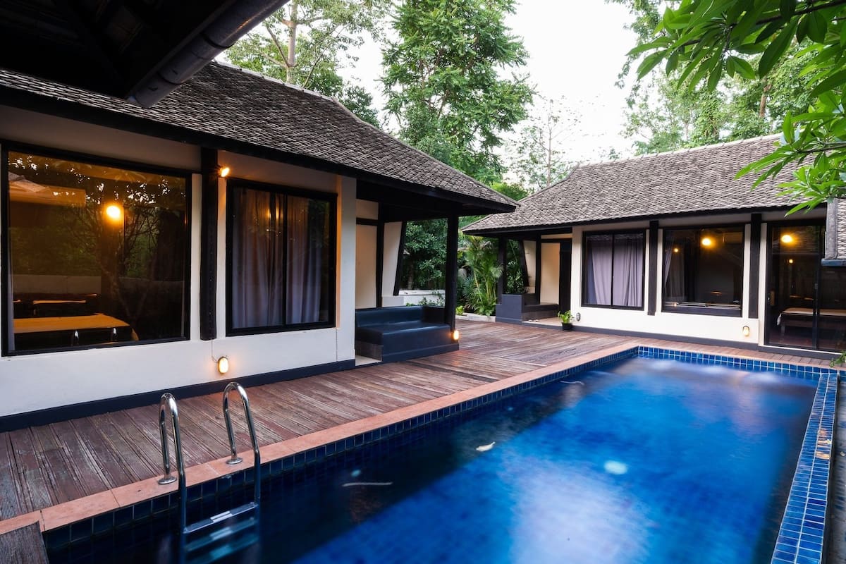 A modern villa with a swimming pool, large windows, and a wooden deck.