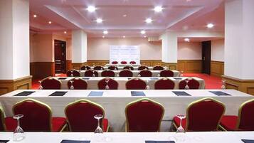 A conference room with rows of tables and chairs, equipped with nameplates and water glasses.