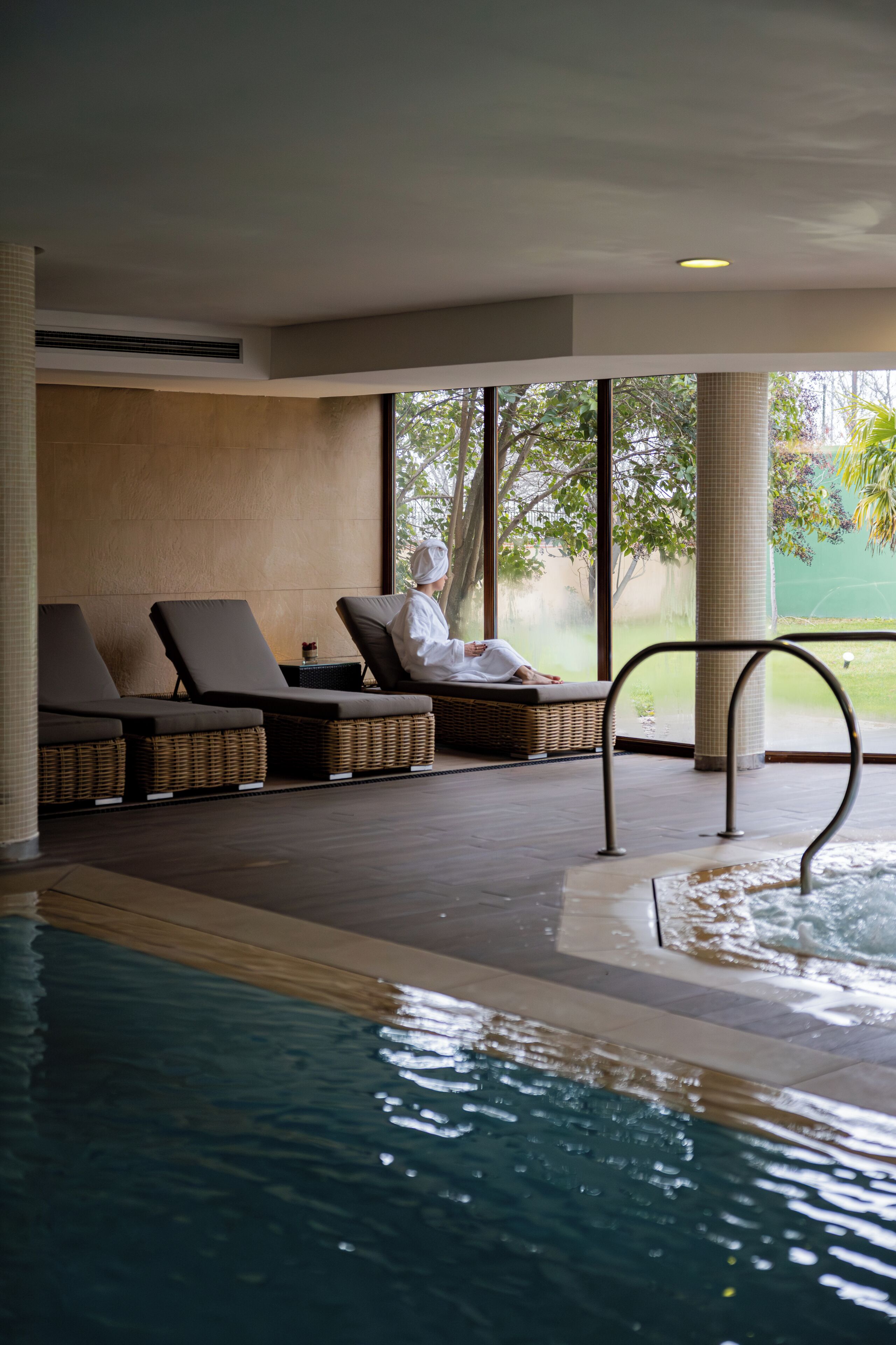 Zona de piscina con sillones reclinables y una persona relajándose.