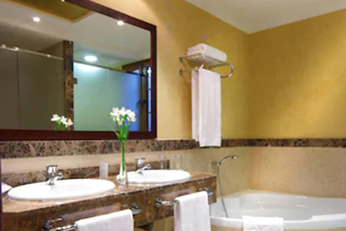 A bathroom with two sinks, a large bathtub, and a mirror.