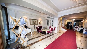 A hotel lobby with a red carpet, white walls, and a chandelier. There are red chairs and a table with a vase. - The And Hotel Istanbul - Special Class (Istanbul)