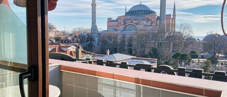 A balcony with a view of a historic building with multiple domes and minarets.