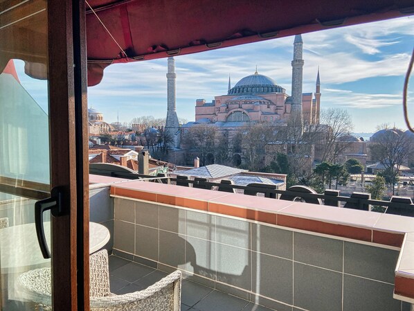A balcony with a view of a historic building with multiple domes and minarets.