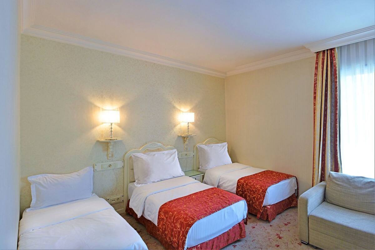 A hotel room with two beds, a chair, and two bedside lamps.